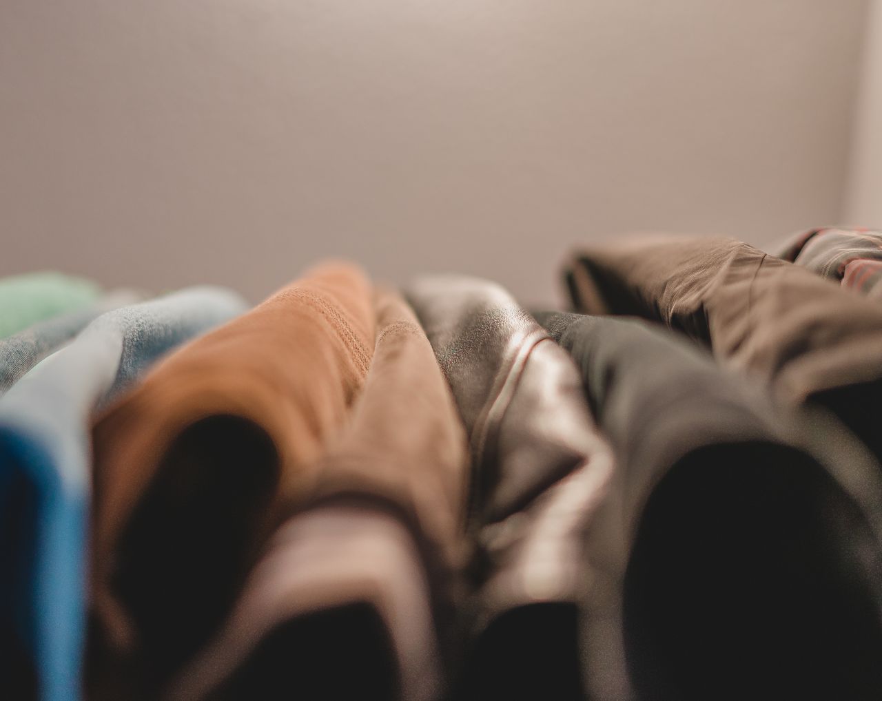 A textured close-up of colorful folded fabrics showing a variety of materials in warm lighting.